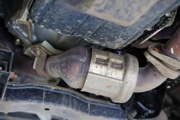 Damaged catalytic converter under a vehicle causing reduced engine performance and a check engine light.