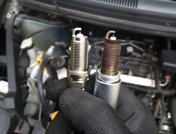 Worn spark plugs removed from a car engine during maintenance to diagnose engine misfire and check engine light issues.