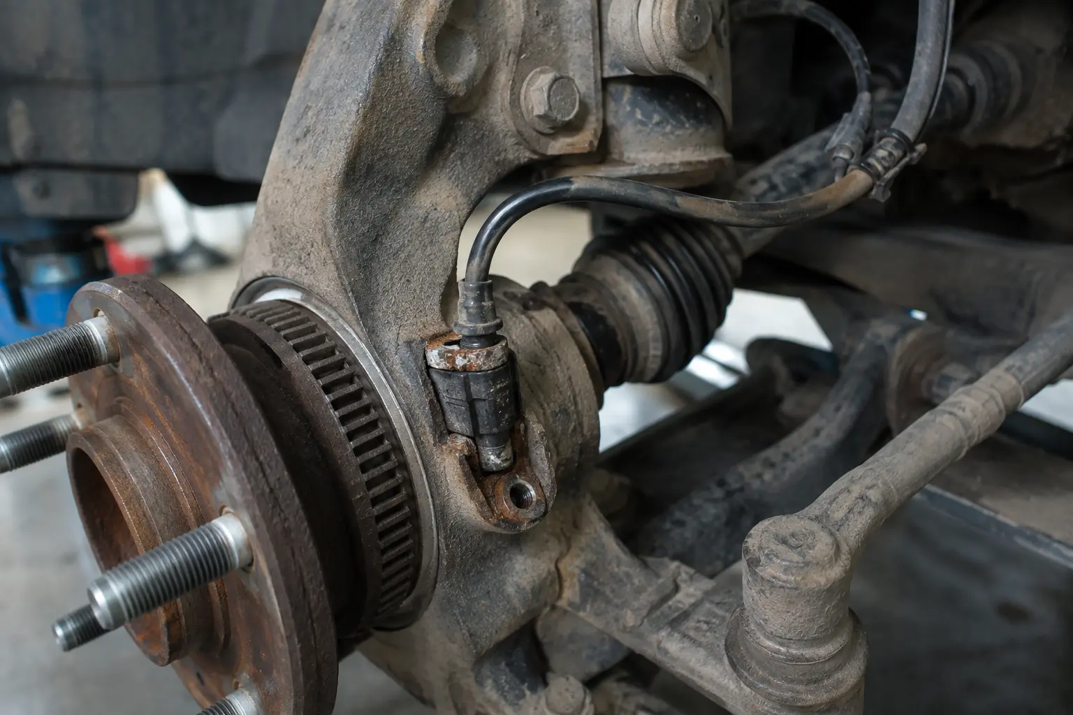 Technician replacing a faulty ABS wheel speed sensor that can affect the TPMS warning system.