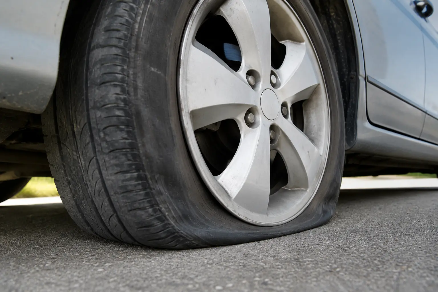 Mechanic checking low tire pressure on a car tire using a digital tire pressure gauge.