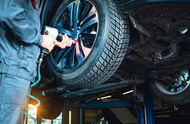 Technician installing new tires and wheels with TPMS sensors during tire replacement on a modern vehicle.
